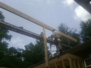 Carpenter setting a ridge beam over a new addition frame — Ice Dam Removal by Roofing Brothers in Johnston